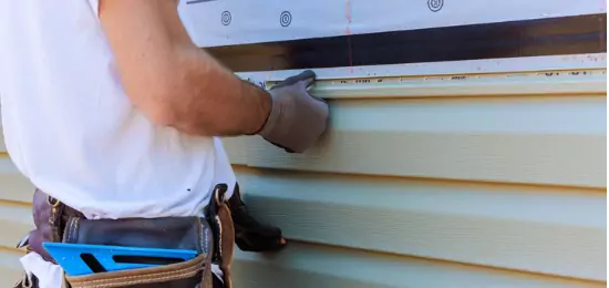 Contractor for Schneider Construction affixing siding to the side of a home in Central Illinois