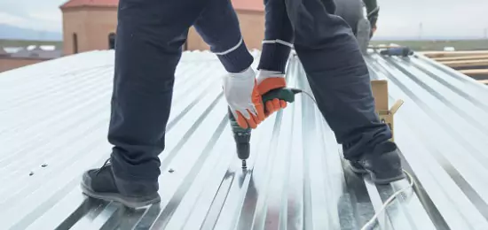 A man installing a flat metal sheets onto a commercial roof