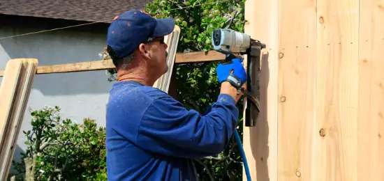 A contractor for Schneider Construction installing a wood fence around a home in Central Illinois